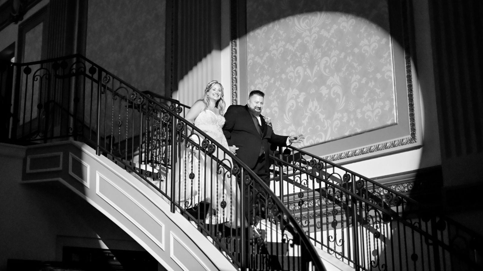 A couple walking down the Grand Staircase at Vault 634 with the spotlight on them